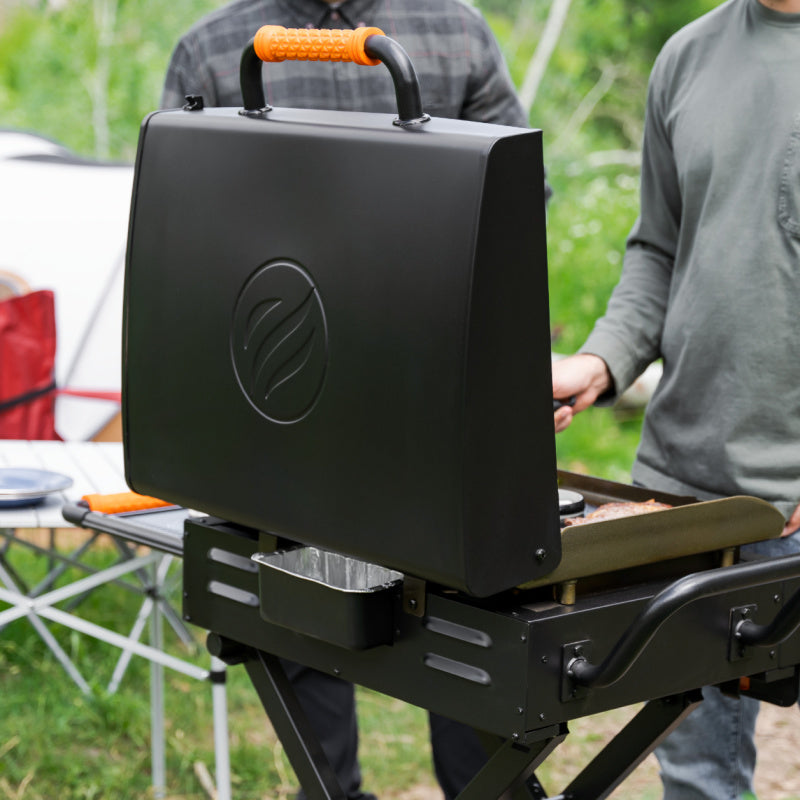 Blackstone 2350 22 inch On The Go Omnivore FlexFold Griddle Cooking outdoors with open hood and drip tray at the rear