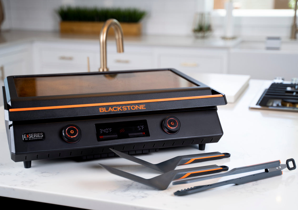 Blackstone 22inch E Series Electric Griddle on white bench with accessories