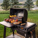 Traeger Woodridge outside grilling food on patio right angle